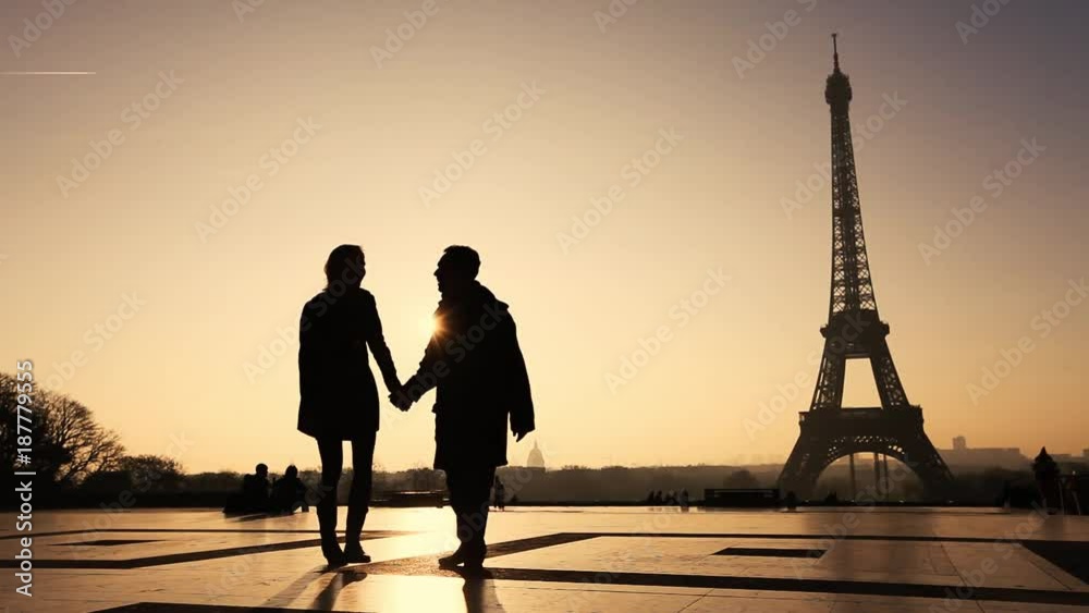 happy affectionate couple in Paris near Eiffel tower, silhouettes of man and woman on honeymoon in Europe