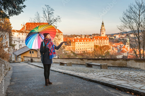 Happy young woman with umbrella travelling in Cesky Krumlov at winter