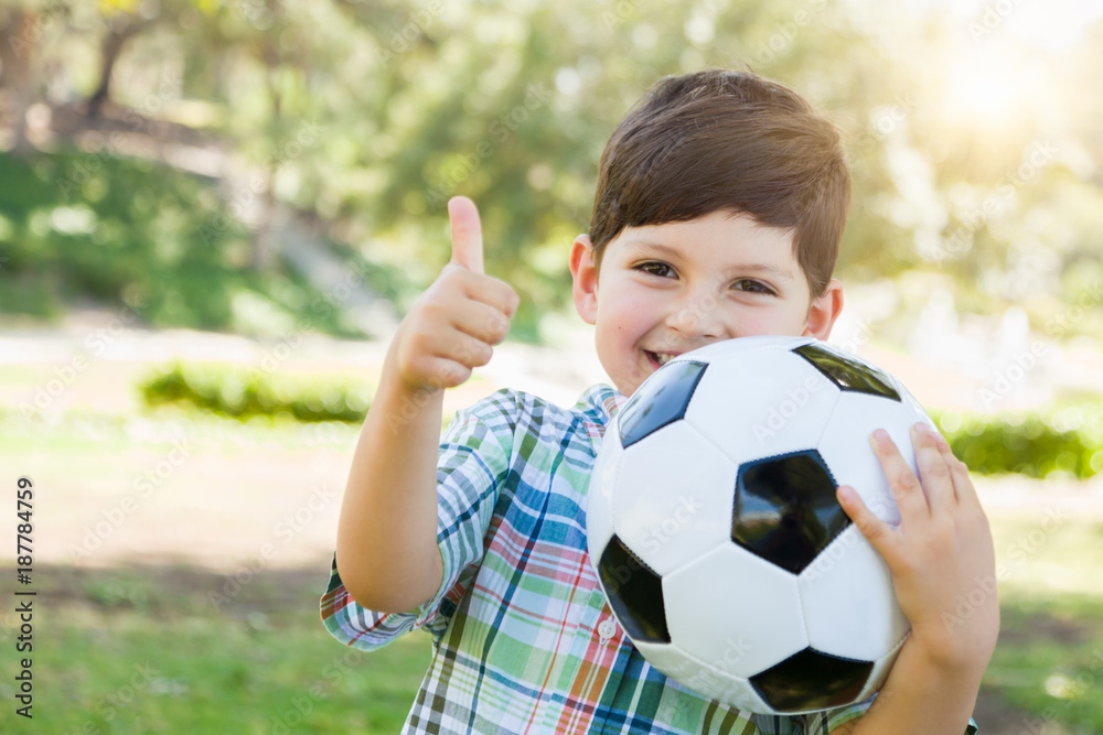 Cute Young Boy Playing with Soccer Ball and Thumbs Up Outdoors in the Park. Cute Young Boy Playing with Soccer Ball and Thumbs Up Outdoors in the Park.