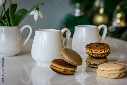 Close up of a jug of milk and french macaroon with a taste of caramel and chocolate on a white background, shallow depth of focus. Concept Valentine day.