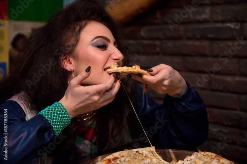 brunette with appetite eating pizza in cafe