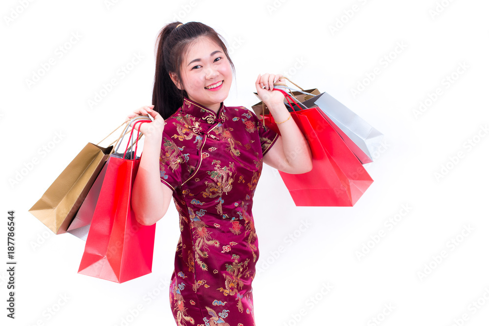 Young asian woman wearing chinese dress traditional cheongsam with Carrying a shopping bag and smile. Chinese New Year Festivities, New Year Celebration, Shopping concept, on white background. Young asian woman wearing chinese dress traditional cheongsam with Carrying a shopping bag and smile. Chinese New Year Festivities, New Year Celebration, Shopping concept, on white background.
