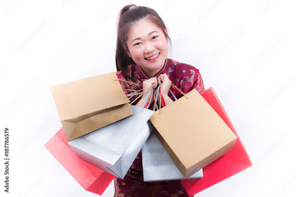 Young asian woman wearing chinese dress traditional cheongsam with Carrying a shopping bag and smile. Chinese New Year Festivities, New Year Celebration, Shopping concept, on white background. Young asian woman wearing chinese dress traditional cheongsam with Carrying a shopping bag and smile. Chinese New Year Festivities, New Year Celebration, Shopping concept, on white background.