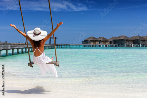 Attraktive Frau im weißen Kleid genießt ihren Sommerurlaub am tropischen Strand der Malediven photo