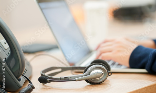 Bild auf Leinwand close up headset device with employee man working by typing on laptop for contac