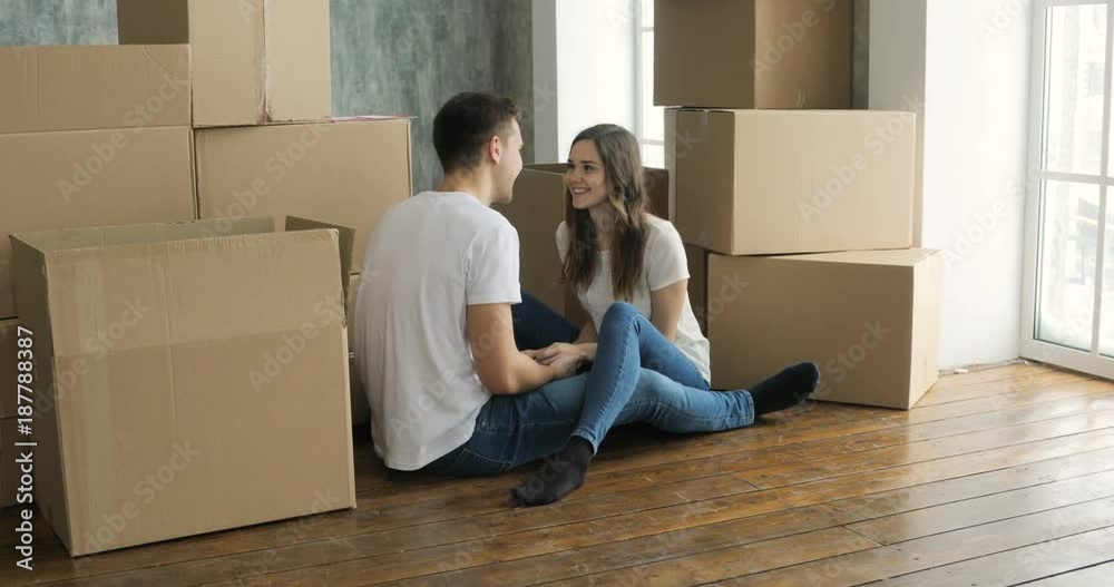 Young couple relaxing laughing after unpacking cartons from house move Young couple relaxing laughing after unpacking cartons from house move