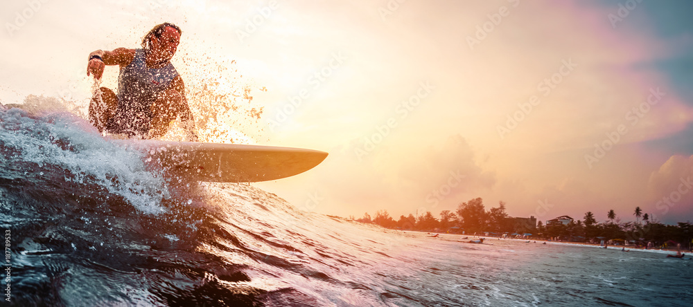 Fototapeta Surfer jeździ fal oceanu podczas zachodu słońca. Sport ekstremalny i koncepcja aktywnego stylu życia
