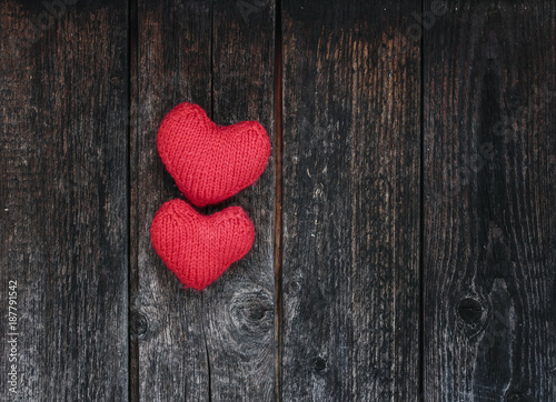 two bright red hearts made of yarn on a background of the wooden walls of old dark tar boards