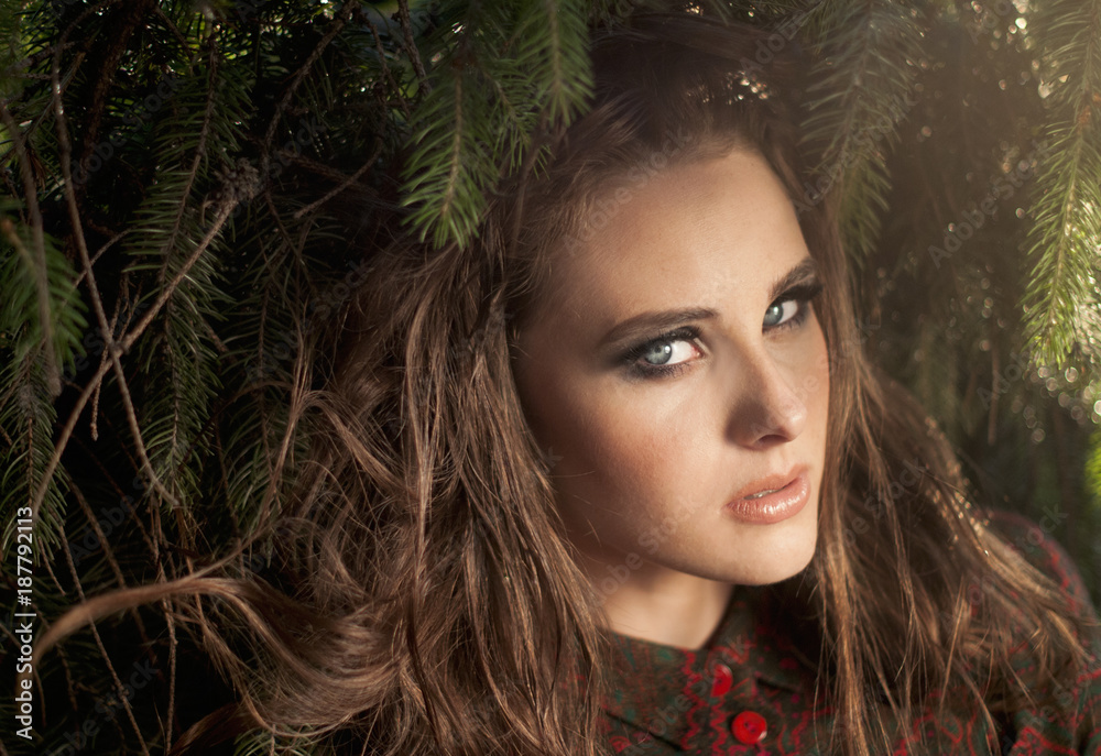 Charming girl with blue eyes and tangled hair in spruce Charming girl with blue eyes and tangled hair in spruce