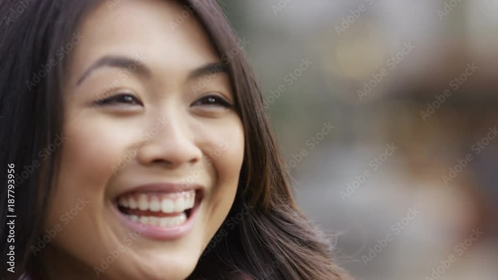 Young attractive chinese female talking to someone off camera with a happy expression