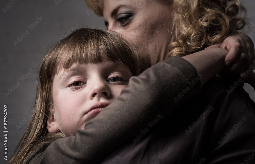 Photo shooting indoors. On the background of a white brick wall . Child ( girl ) hugs his mother.
