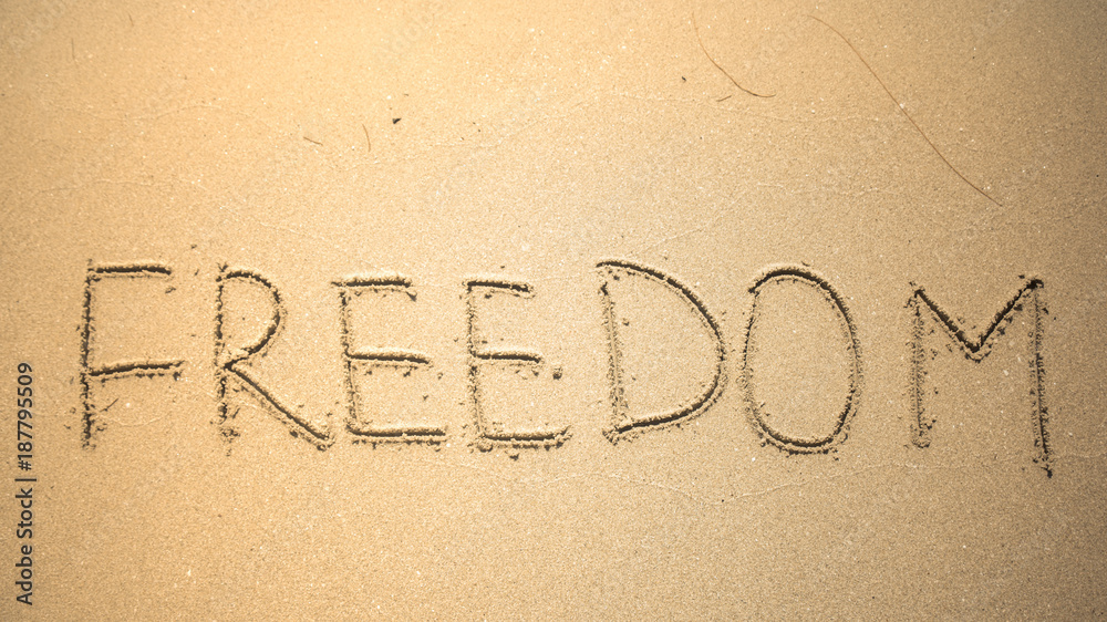 Freedom word is written on the beach sand