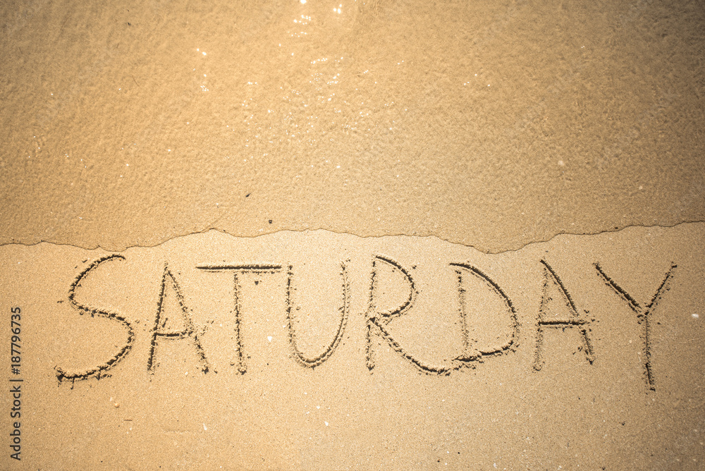 Fototapeta premium Saturday word is written on the beach sand
