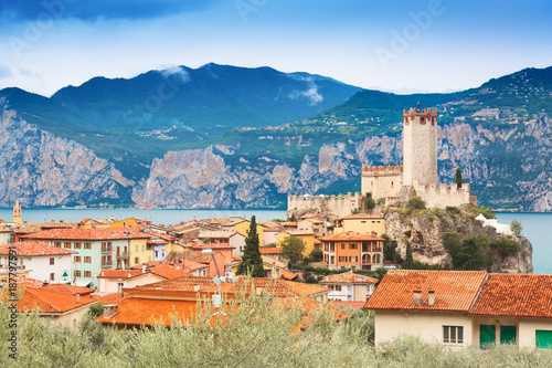 Ancient tower and fortress in old town Malcesine at Garda Lake. Mountains with clody sky in the background. Italian landscape. Small town Malcesine near Monte Baldo mountain, Italy.