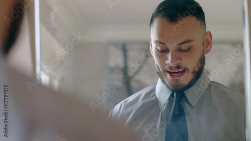 Nervous hispanic man practicing sales pitch in mirror as he gets ready