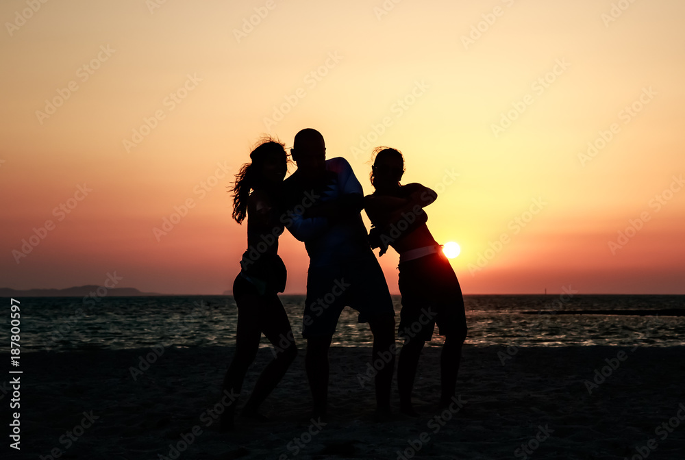 People friends company silhouettes on the uninhabited island at the sea, orange sunset sky and sea background, Africa, Egypt. Red Sea. Dancing and jumping happy blessed people, beach party, rest time