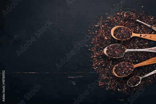 Black wild dry rice on a spoon. On a wooden background. Top view. Copy space.