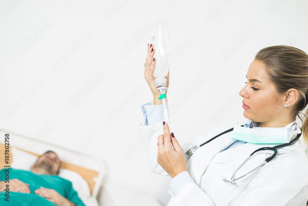 Female doctor prepares an injection while the patient is in bed Female doctor prepares an injection while the patient is in bed