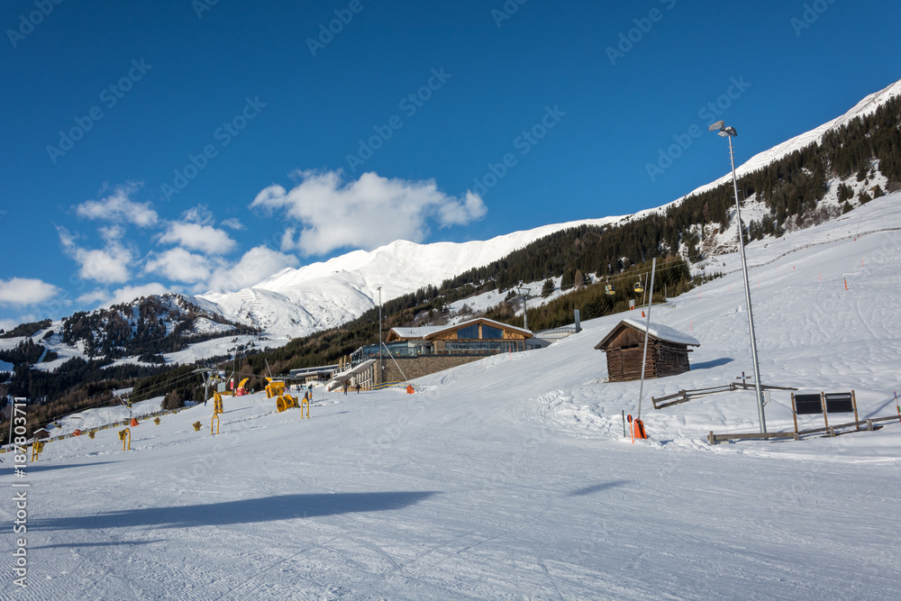 Slope and yellow gondolas with chalet in ski resort Serfaus Fiss Ladis in Austria with snowy mountains