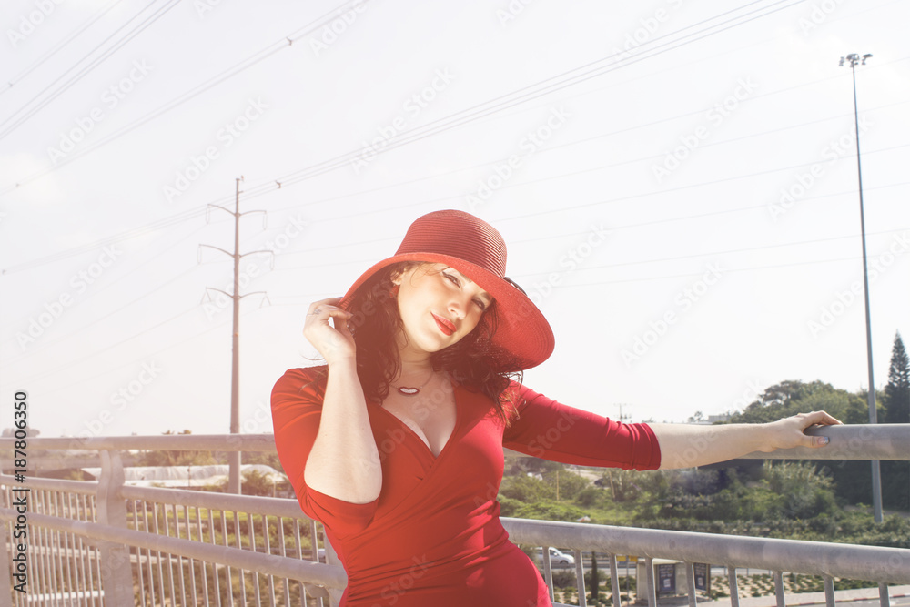 portrait of fashion woman in red dress and hat on the bridge
