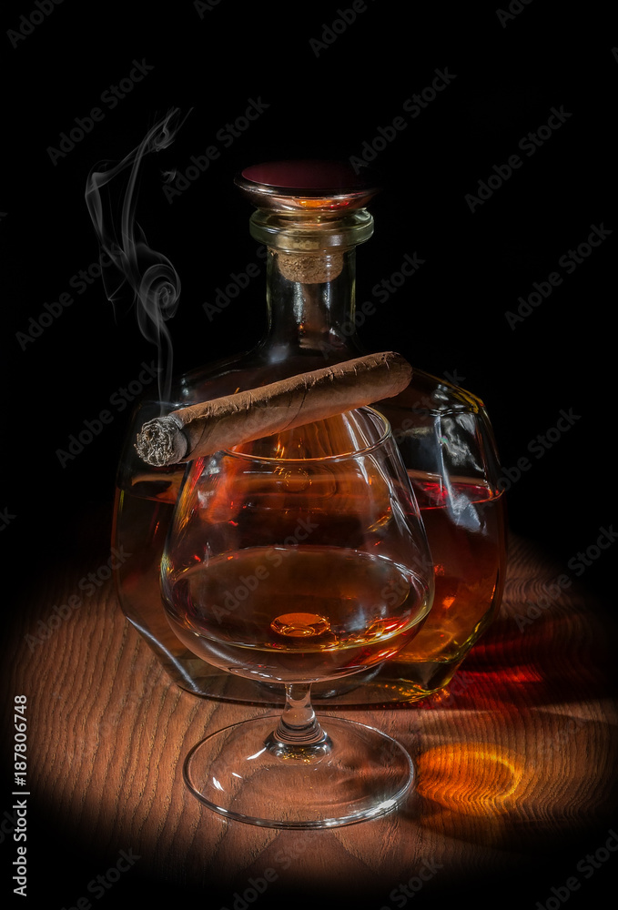 A glass of cognac with a cigarette and a bottle of cognac A glass of cognac with a cigarette and a bottle of cognac