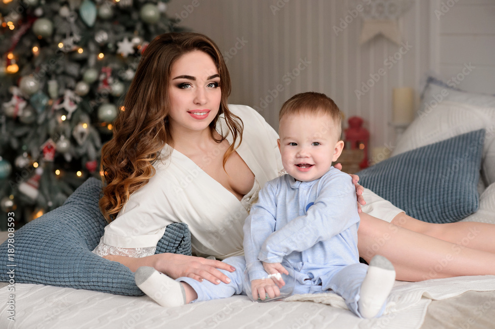 Merry Christmas celebration. Beautiful mom and little son at home near the Christmas tree. Christmas miracles. Happy New Year Merry Christmas celebration. Beautiful mom and little son at home near the Christmas tree. Christmas miracles. Happy New Year