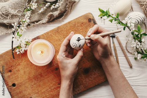 hand painting modern easter egg top view. preparation for holiday, easter celebration. stylish  painted egg. process of coloring eggs with wax and candle. family traditions. flat lay photo