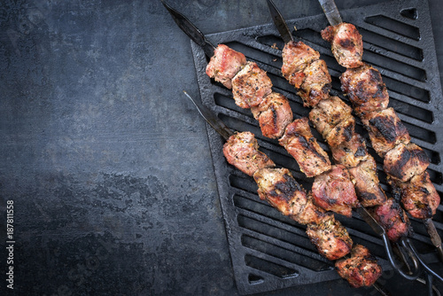 Fotografi Traditional Russian shashlik on a barbecue skewer as top view on grillage with c