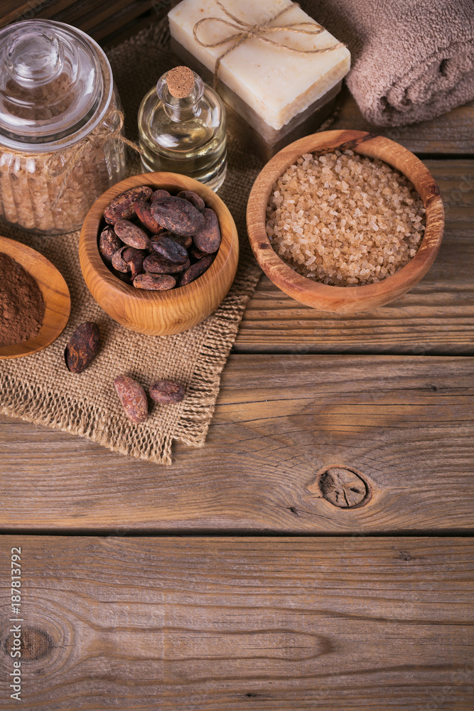 Fototapeta premium Natural cosmetic oil, sea salt and natural handmade soap with cocoa beans on rustic wooden background