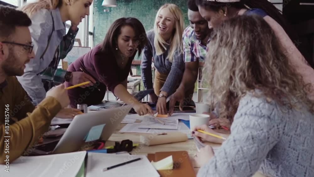 Top view of young team working on architectural project. Group of mixed race people standing near table and discussing.
