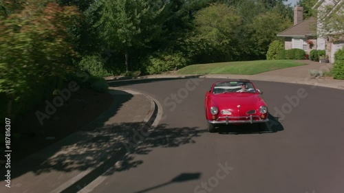 Tracking shot of man driving classic convertible car through neighborhood.  Fully released for commercial use.