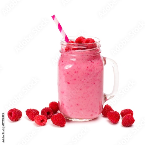 Raspberry smoothie in a mason jar glass with straw and scattered berries isolated on white