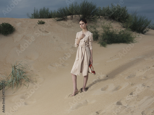 Portrait of woman wearing dress standing on the beach carrying shoes