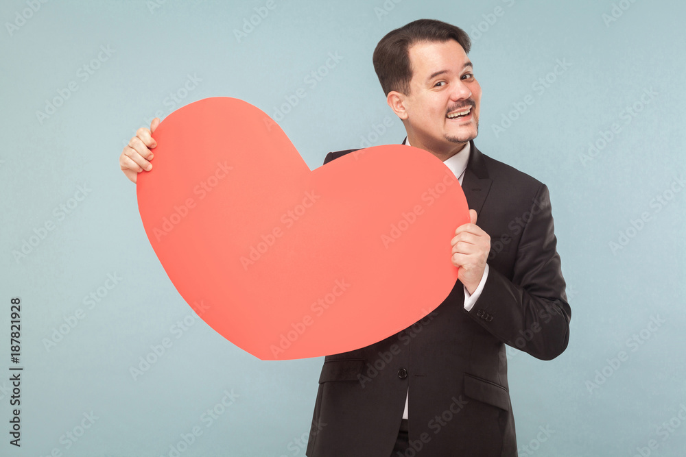 Bearded businessman holding big red heart and toothy smiling Bearded businessman holding big red heart and toothy smiling