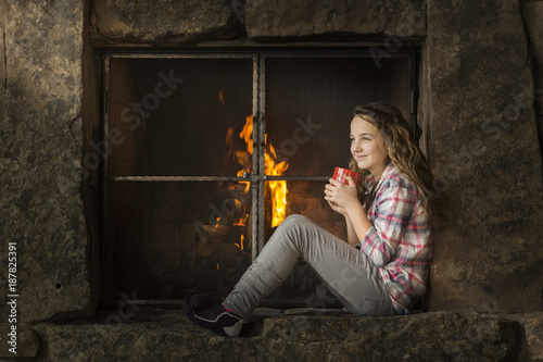 Smiling Caucasian girl sitting near fireplace photo