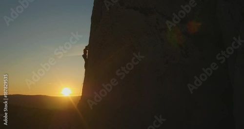Aerial lift - Man rock climbing outdoors at amazing sunset.
