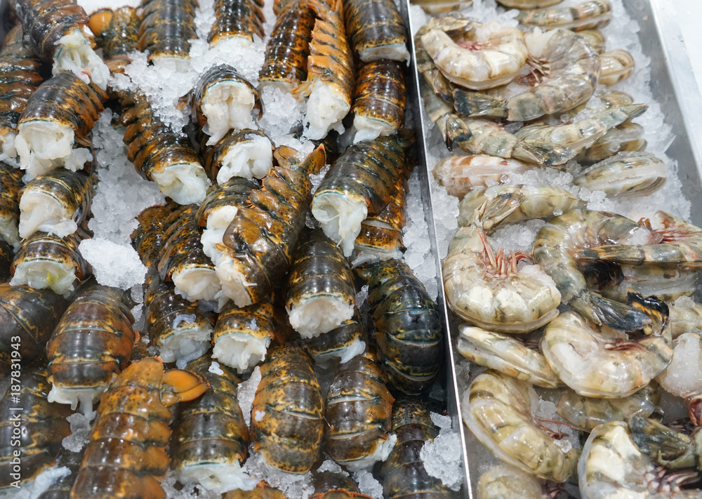 Raw lobster tail and shrimp frozen on the ice for sale
