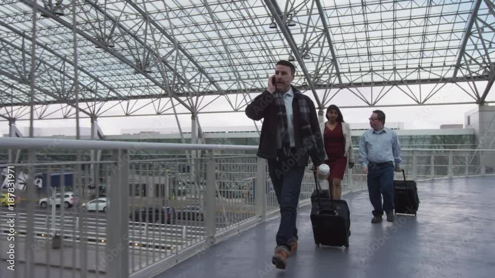 Businessman walking and talking on cell phone at airport Businessman walking and talking on cell phone at airport