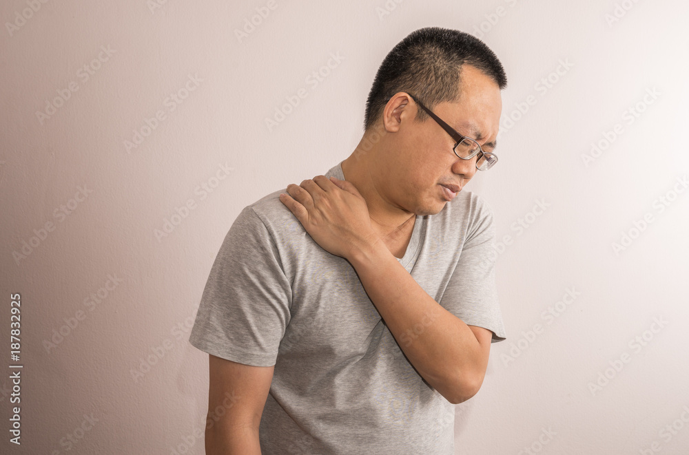 Middle aged Asian man having shoulder pain. Man wear eyeglasses. Use one hand touch shoulder. Middle aged Asian man having shoulder pain. Man wear eyeglasses. Use one hand touch shoulder.
