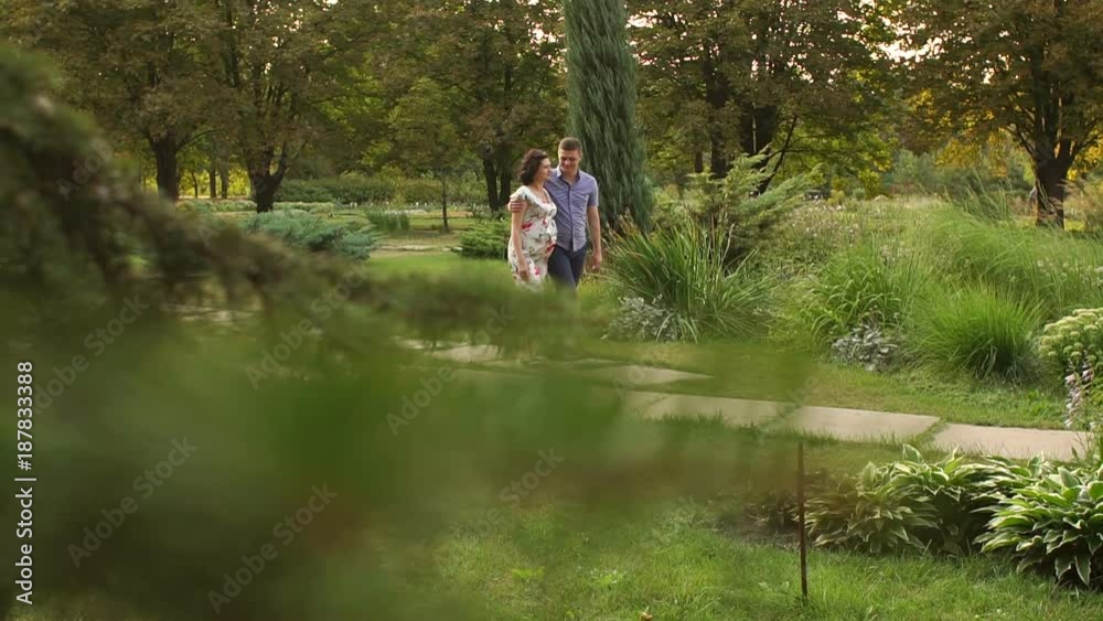 A pregnant woman and her husband walking in summer Park at sunset. Slow motion. Happy family expecting a baby. A pregnant woman and her husband walking in summer Park at sunset. Slow motion. Happy family expecting a baby.