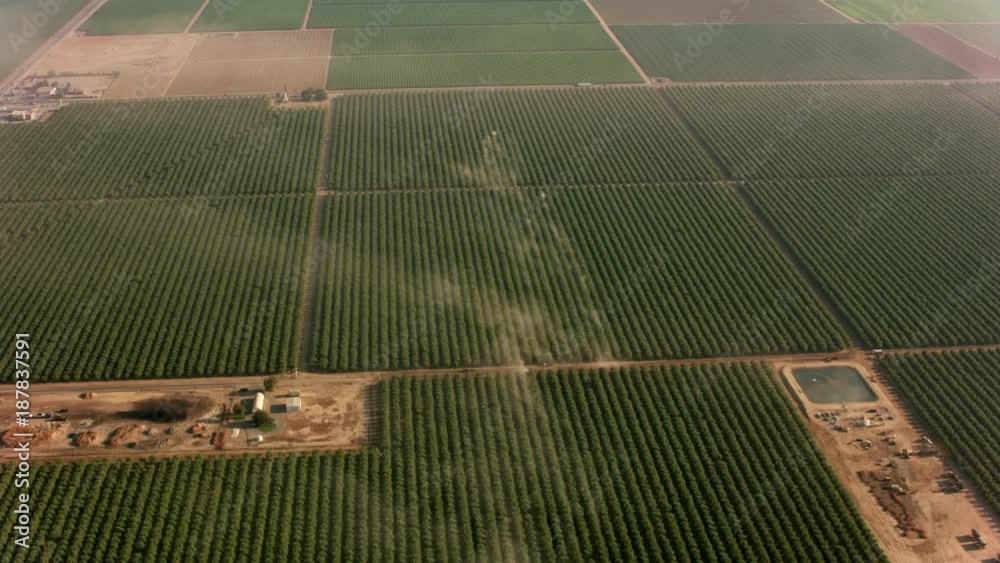 California circa-2017, Aerial shot of orchards with tractors making dust.  Shot with Cineflex and RED Epic-W Helium. 