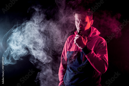 vaping man holding a mod. A cloud of vapor. Black background.