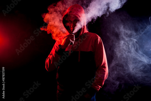 The man smoke an electric cigarette on the bright light background