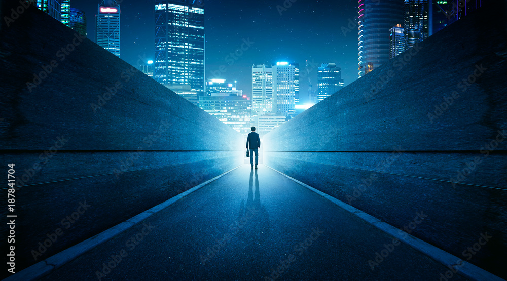 Ambitions concept with businessman walking from alley to modern city . Night scene . - obrazy, fototapety, plakaty 