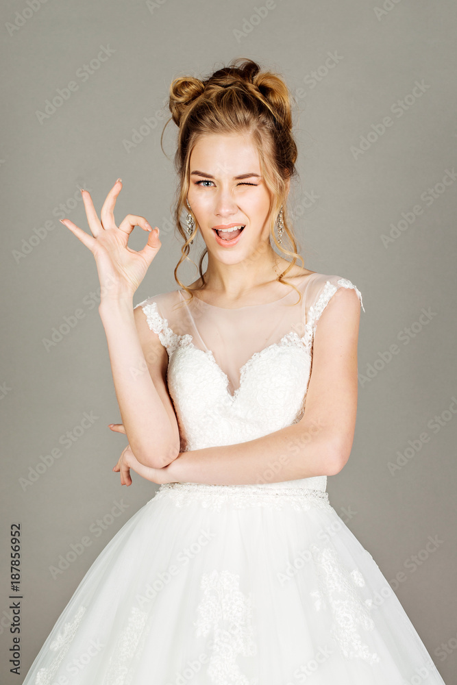young bride showing okay hand sign gesture, on gray background. young bride showing okay hand sign gesture, on gray background.