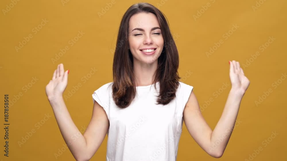 Young cheerful lady standing isolated over yellow background while looking camera. Young cheerful lady standing isolated over yellow background while looking camera.
