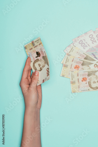 cropped shot of woman with ukrainian money isolated on turquoise photo