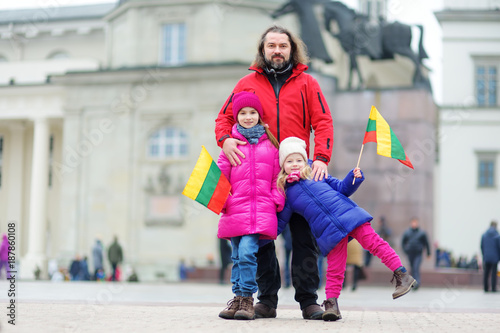 Obraz na płótnie Father and daughters with a flag on Lithuanian independence day holding tricolor