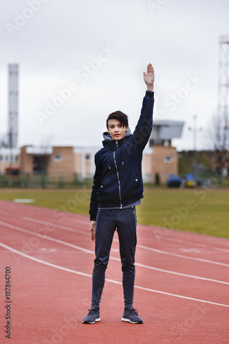 young sportsman makes exercises on a running track © czamfir
