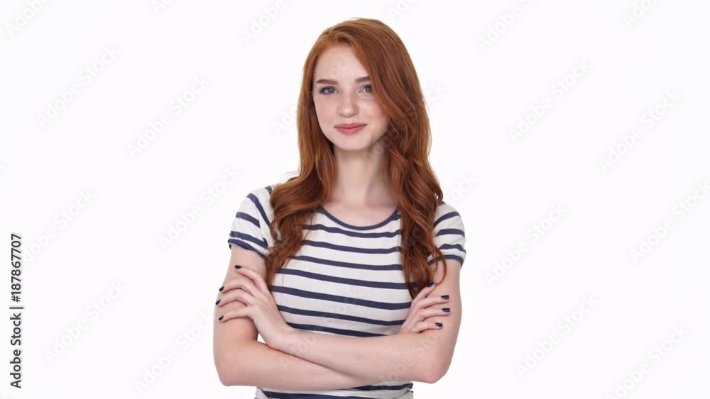 Pretty young cheerful redhead lady looking camera isolated over white wall background with arms crossed Pretty young cheerful redhead lady looking camera isolated over white wall background with arms crossed